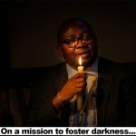 an image of bayo adelabu holding a candle light in a dark room