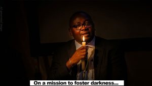 an image of bayo adelabu holding a candle light in a dark room